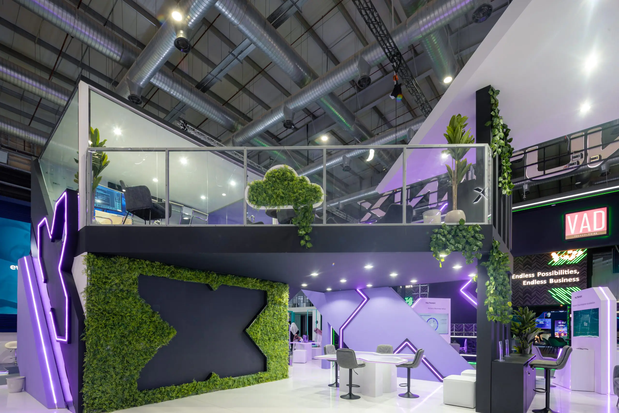 Nutanix booth at the Leap event featuring a two-story design with green and purple accents, a cloud-shaped plant installation, and seating areas.