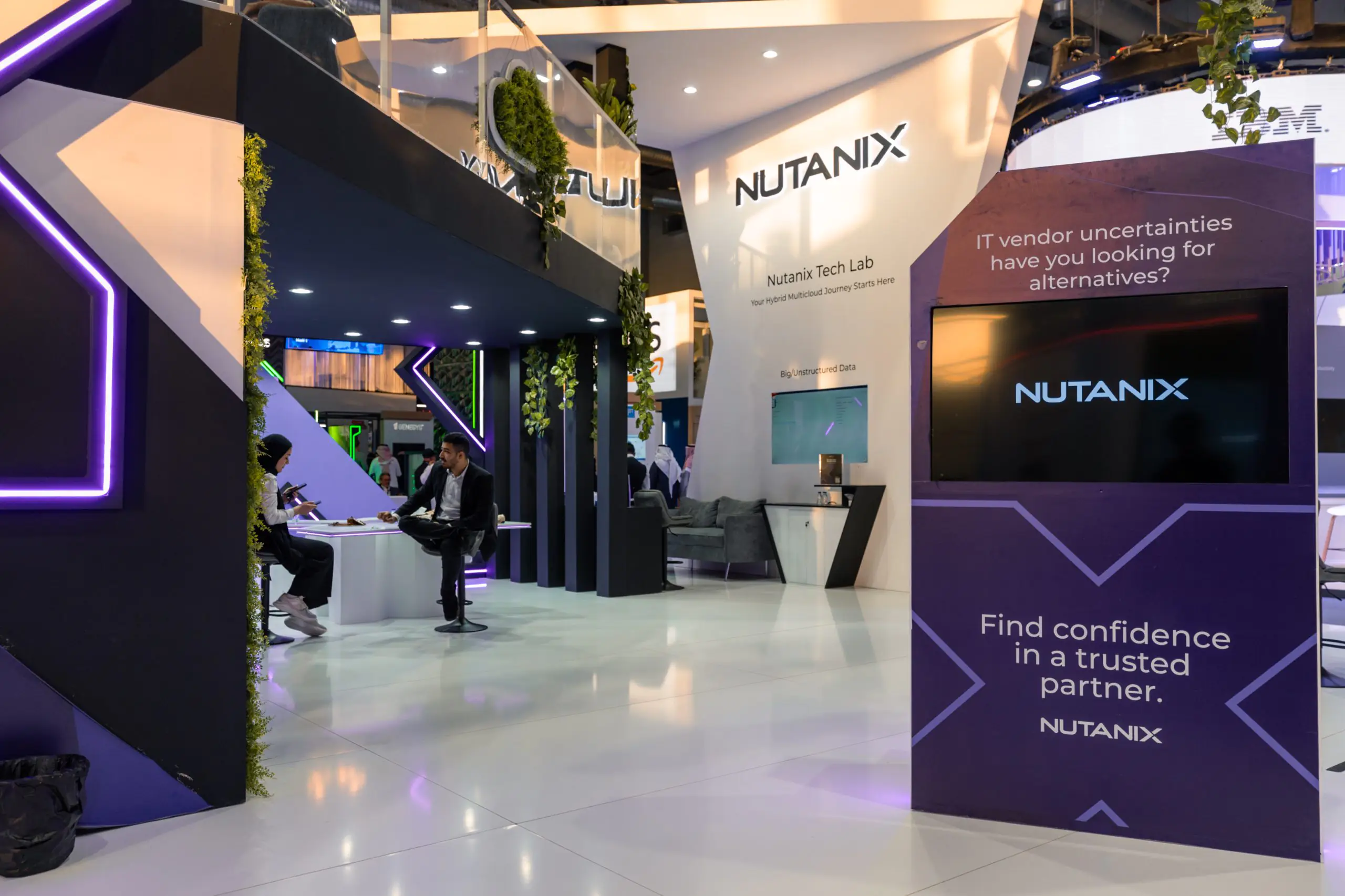 Nutanix booth at LEAP event with purple neon lights, tech lab area, seating space, and a screen displaying Nutanix branding