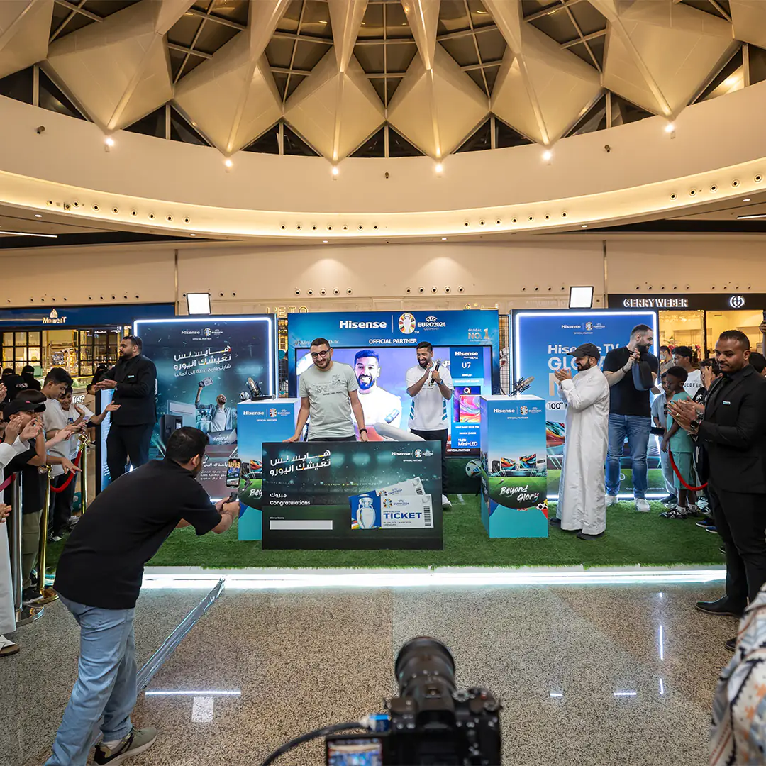 Winner of the Hisense Euro 2024 raffle receiving a prize during a booth event, with audience engagement and influencer Mosaad Al Fozan