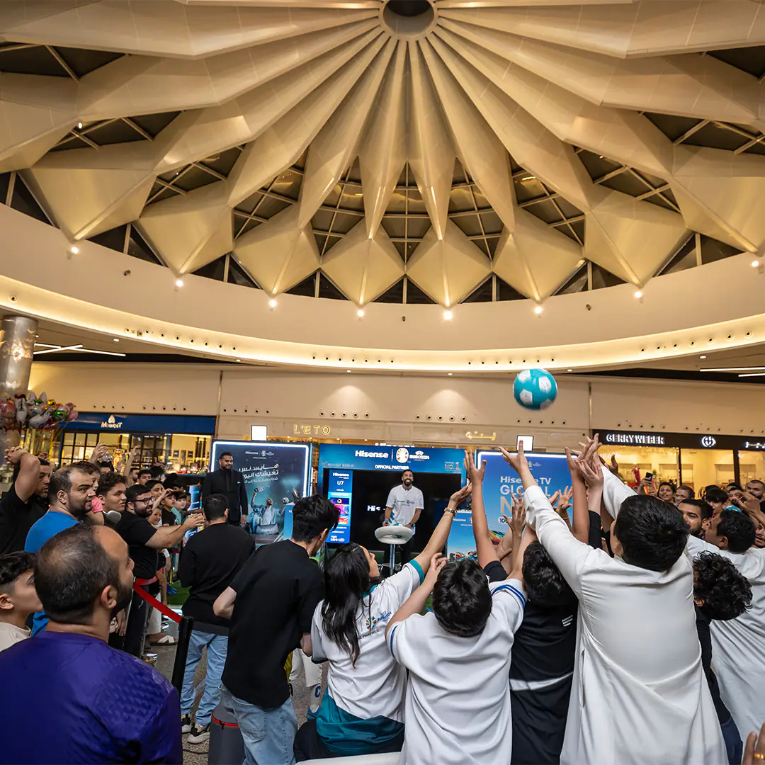 Excited crowd reaching for a football during an interactive game at the Hisense booth, part of the UEFA Euro 2024 promotional event