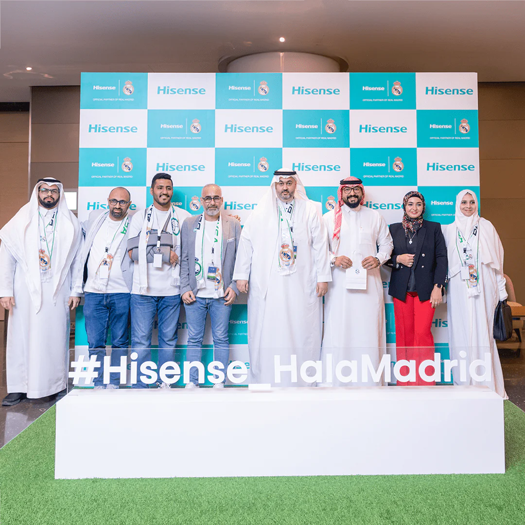 Group of people posing at the Hisense Real Madrid event, with branded backdrop and #Hisense_HalaMadrid sign