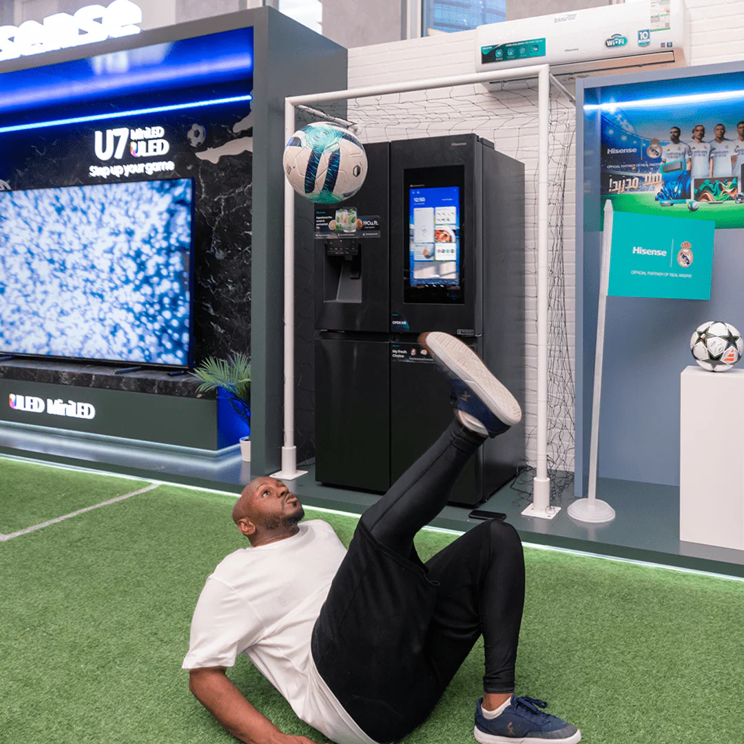 Man performing freestyle football tricks in front of a Hisense display booth, showcasing a fridge and U7 Mini-LED TV