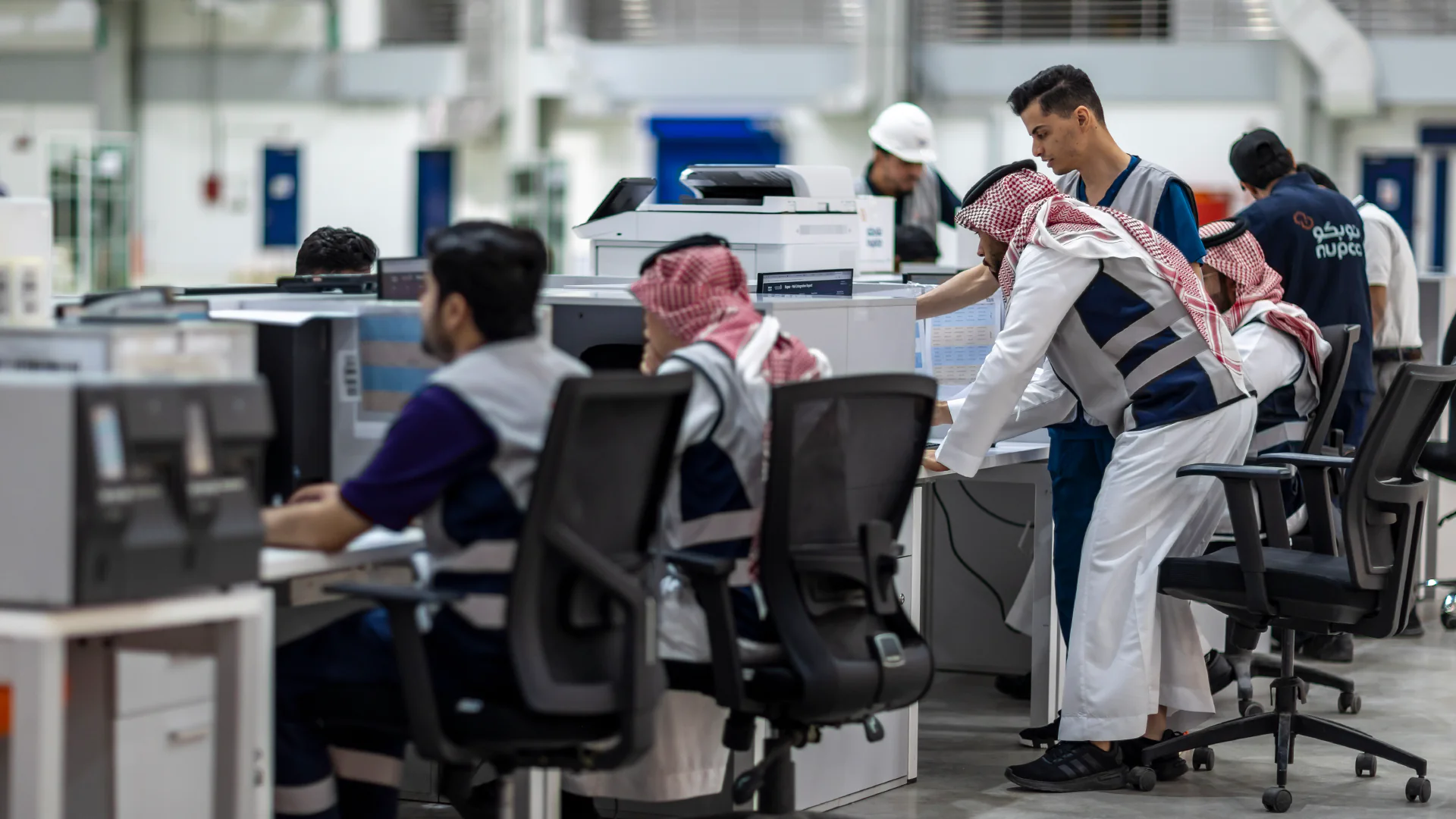 Team of NUPCO employees collaborating in a control room, ensuring smooth operations and efficient management of logistics and distribution processes