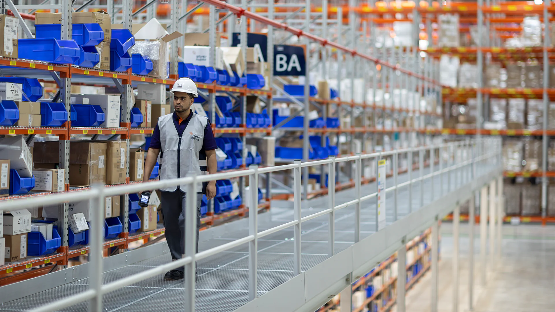 Worker at NUPCO walking through warehouse aisles conducting inventory checks and ensuring stock accuracy and availability