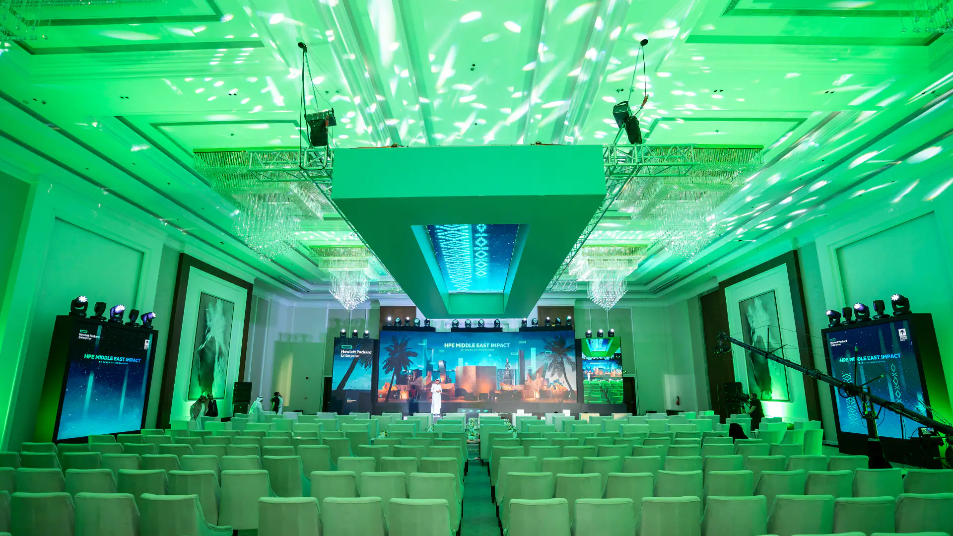 Green-lit auditorium setup for HPE Middle East Impact event, combining modern technology with cultural elements