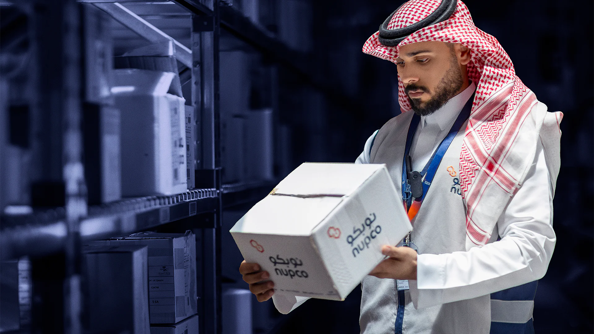 Employee inspecting a NUPCO-branded box in the warehouse, highlighting operational processes within the storage facility