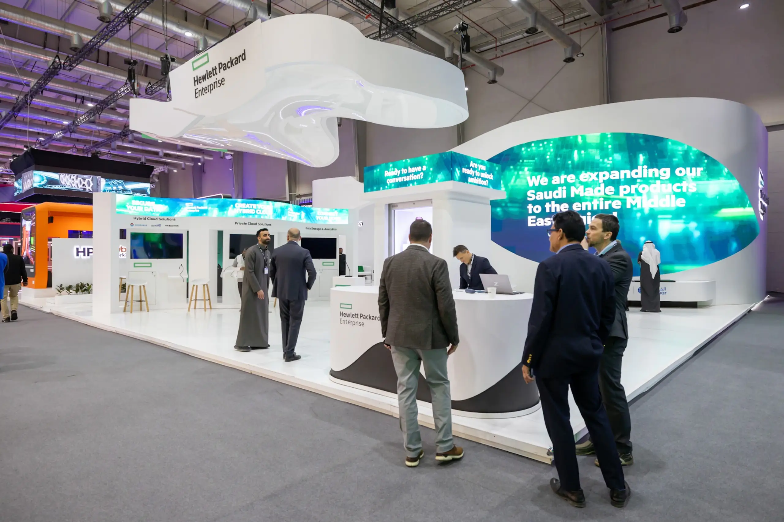 A Hewlett Packard Enterprise exhibition booth with people engaging at the reception and interactive displays.