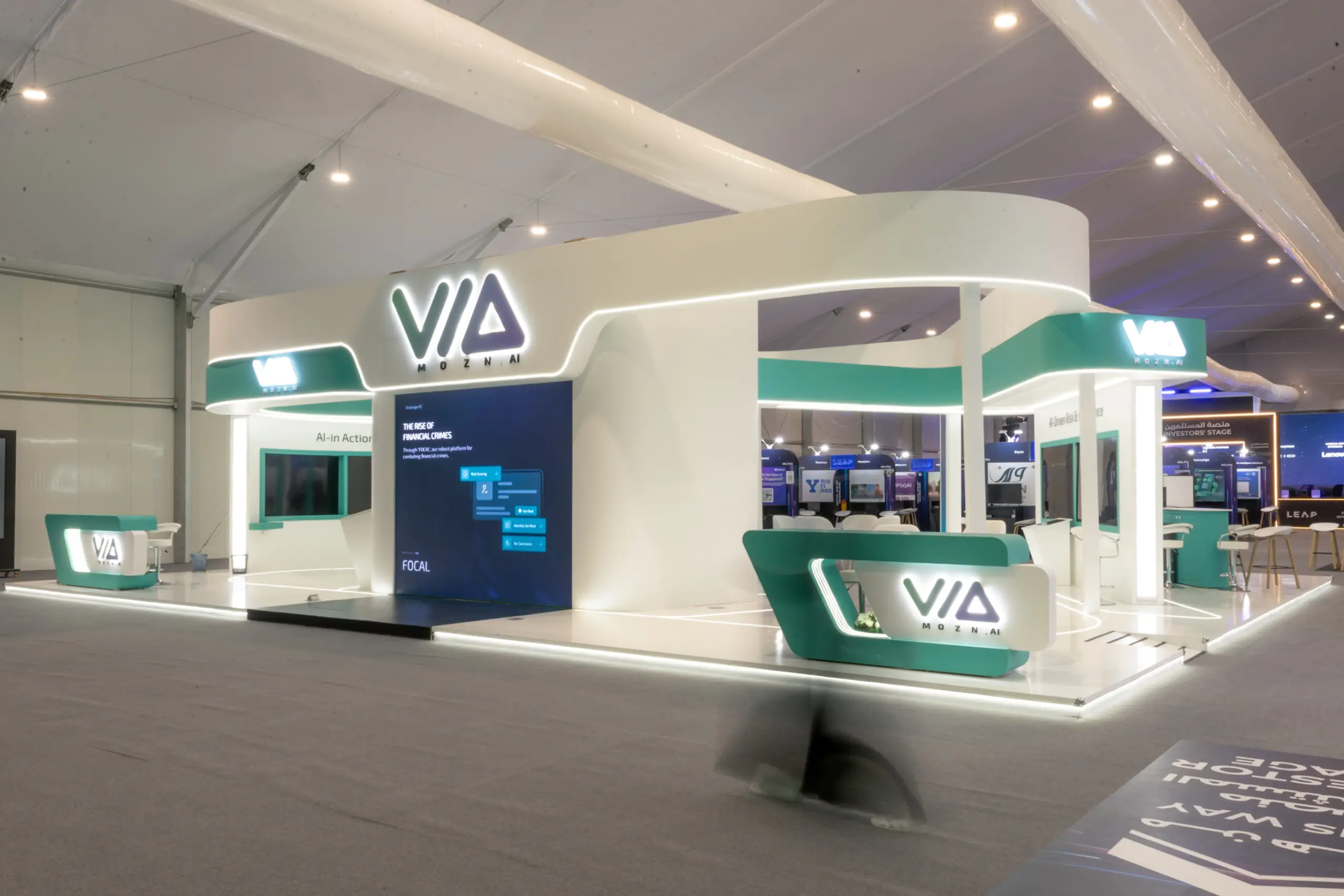 A modern trade show booth with curved structures, illuminated signage, and digital displays showcasing AI-driven solutions.