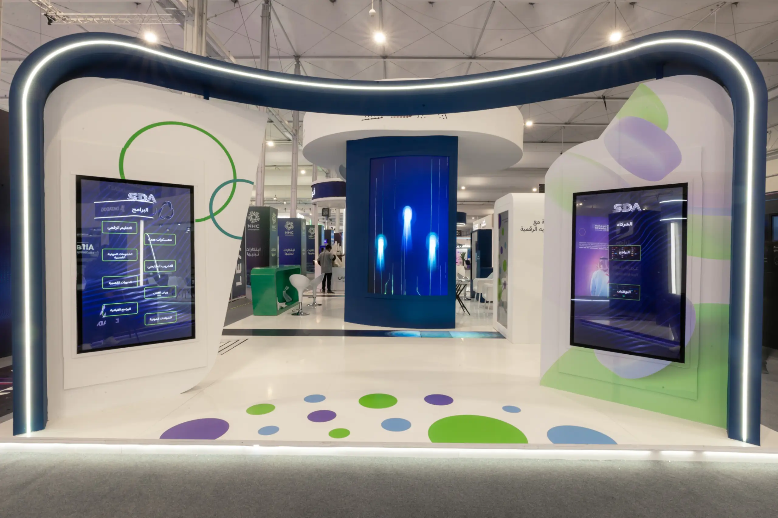 A futuristic exhibition booth with curved LED accents, interactive screens, and a central digital display.