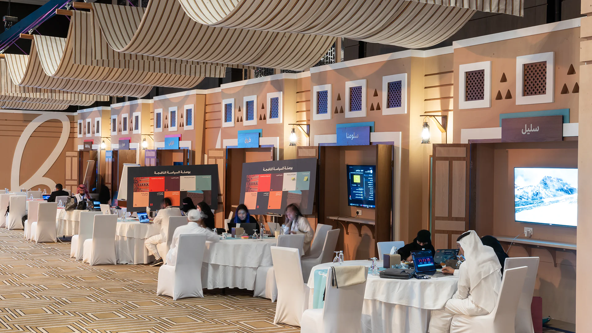 Participants brainstorming at cultural booths under striped canopy panels during the bootcamp.