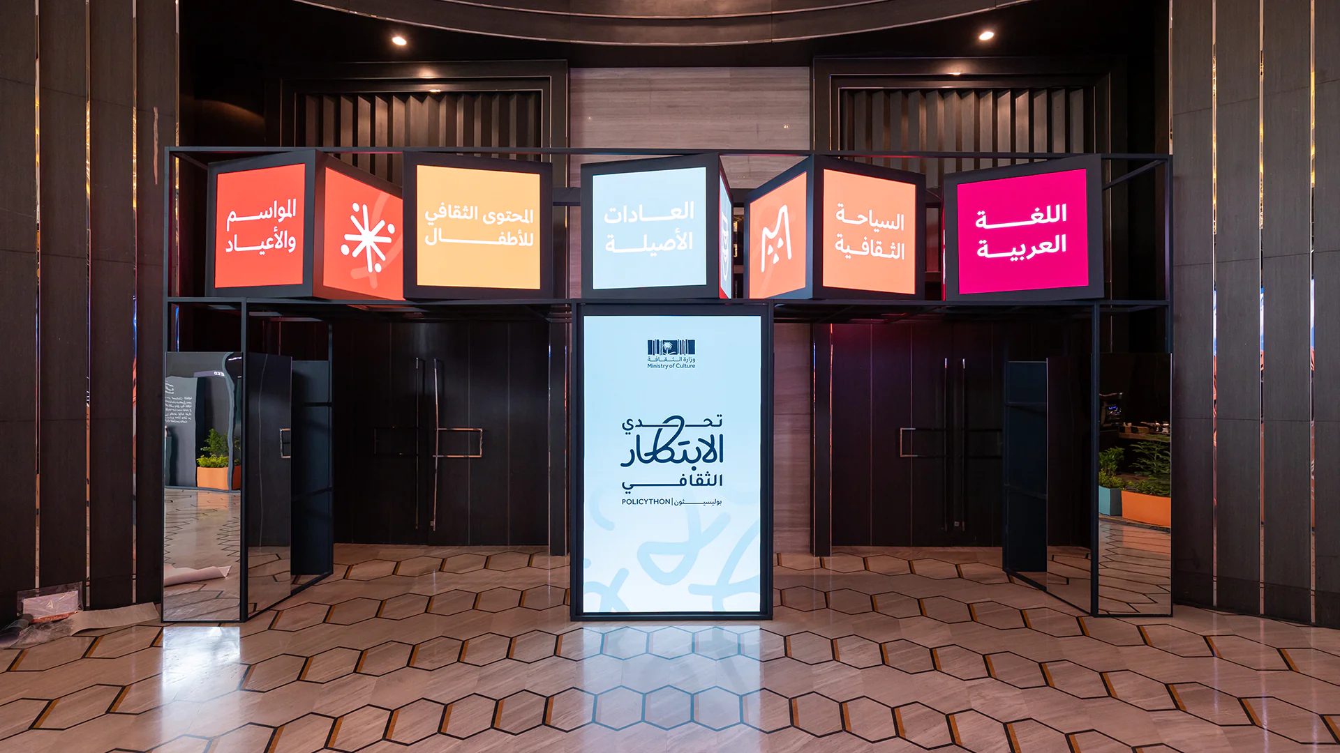 Hanging cubes display Policython themes like Arabic language and cultural tourism at the event entrance.
