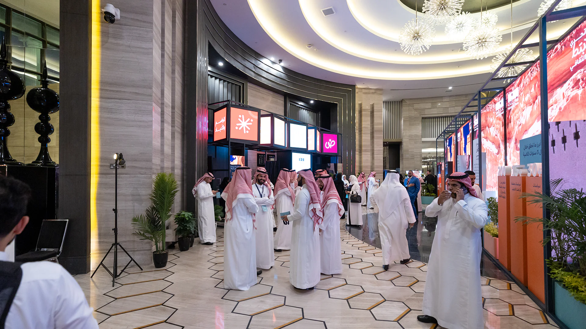 Attendees mingling in the welcome area with hanging theme cubes and visual display panels.