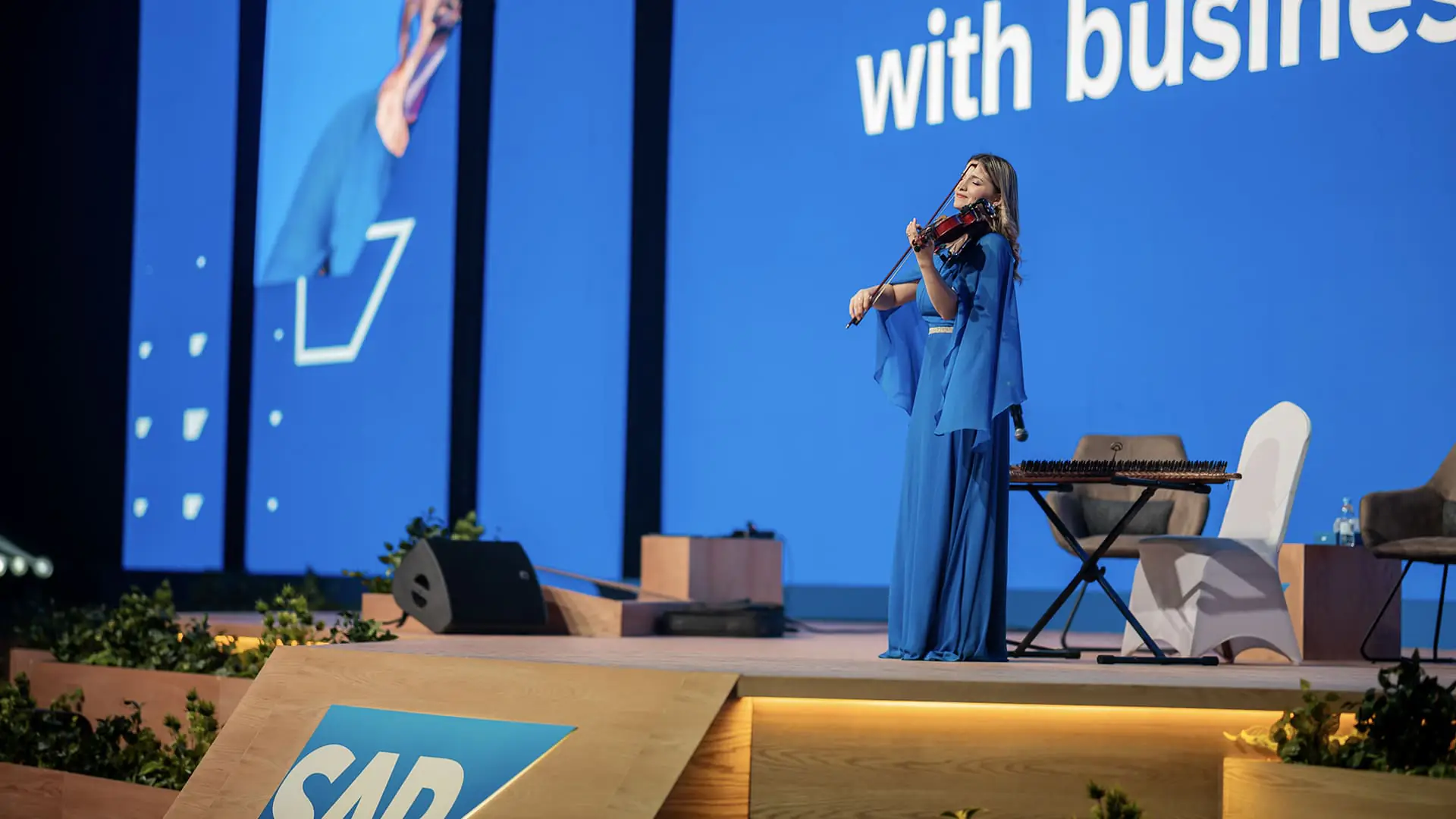 Violinist performs live on the SAP NOW AI Tour stage in front of blue visuals.
