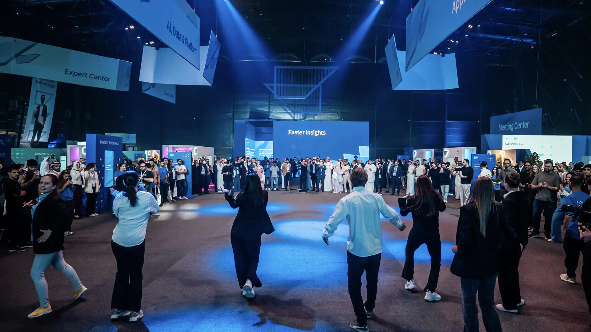 Attendees gather in a circle watching a live activity in the main exhibition hall.
