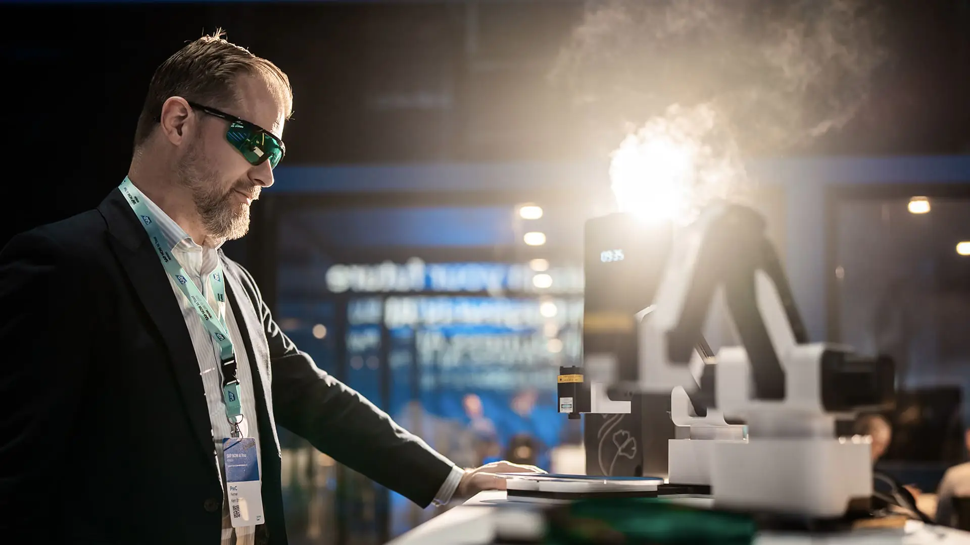 Guest wearing safety glasses interacts with the SAP NOW AI Tour laser engraving station.