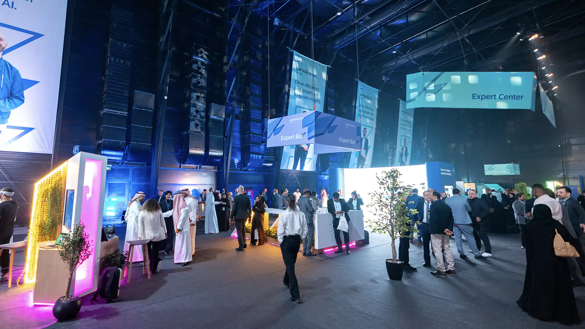 Attendees visit the Expert Bar and booths under blue lighting at SAP NOW AI Tour.