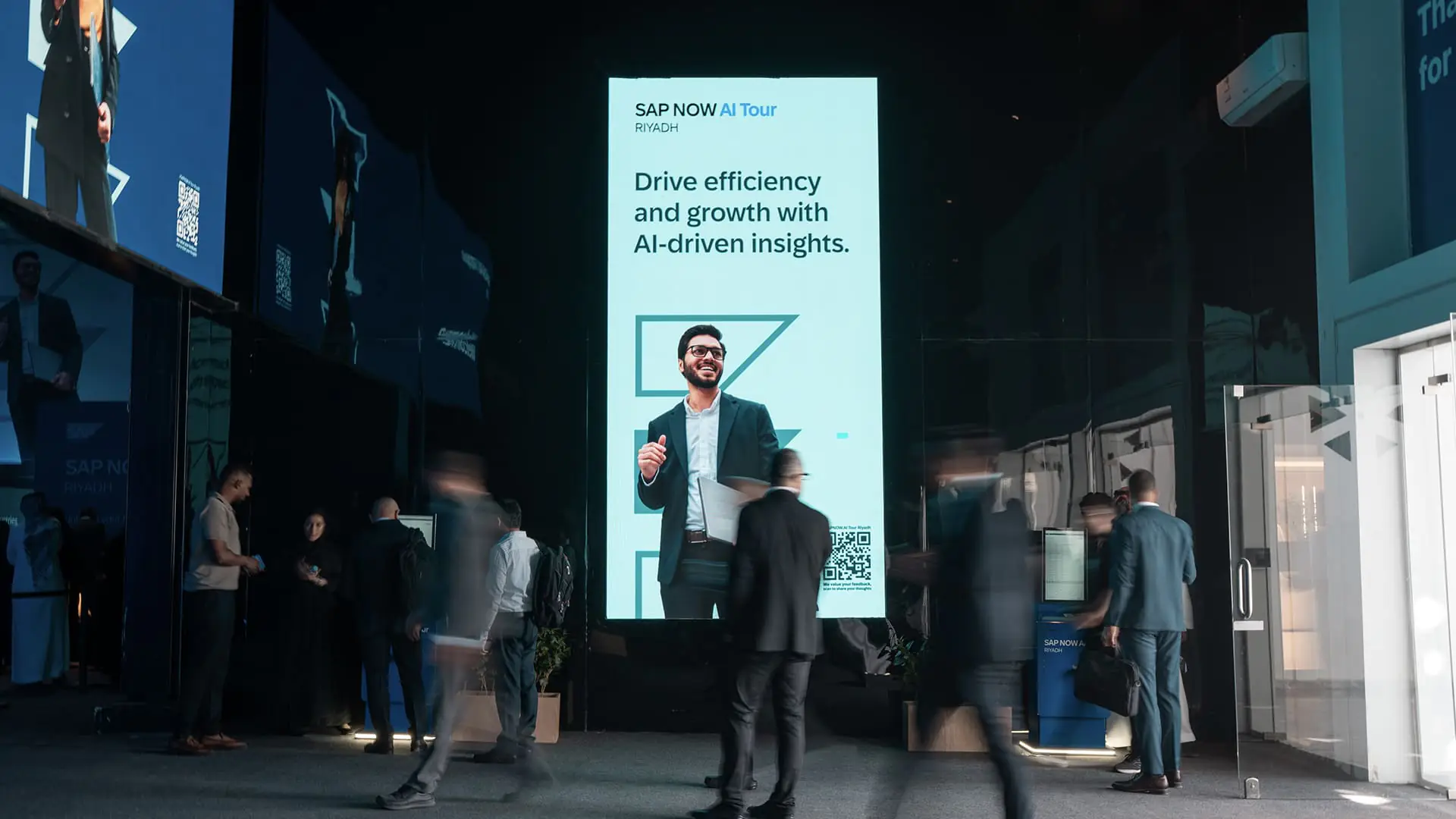 Tall digital screen displays AI-driven insights as attendees move around the venue.