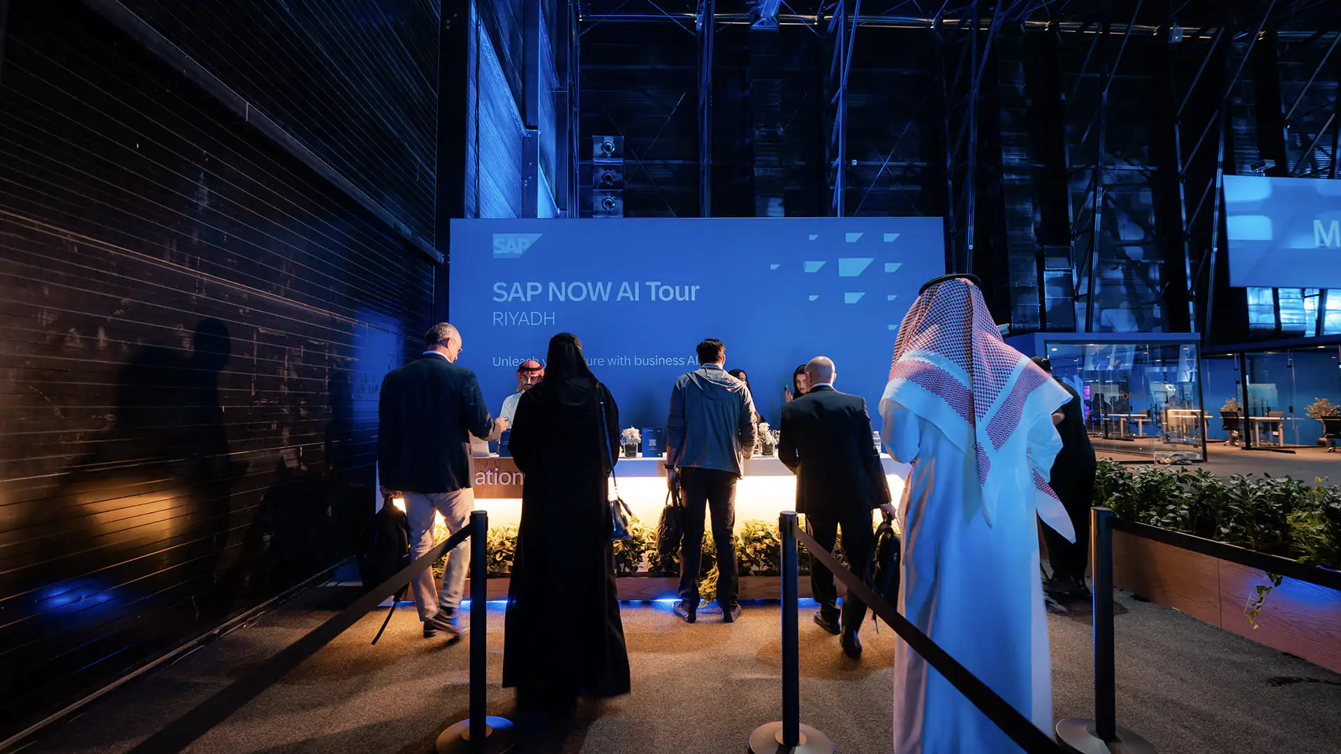 Guests queue at the SAP NOW AI Tour Riyadh registration desk under blue lighting.