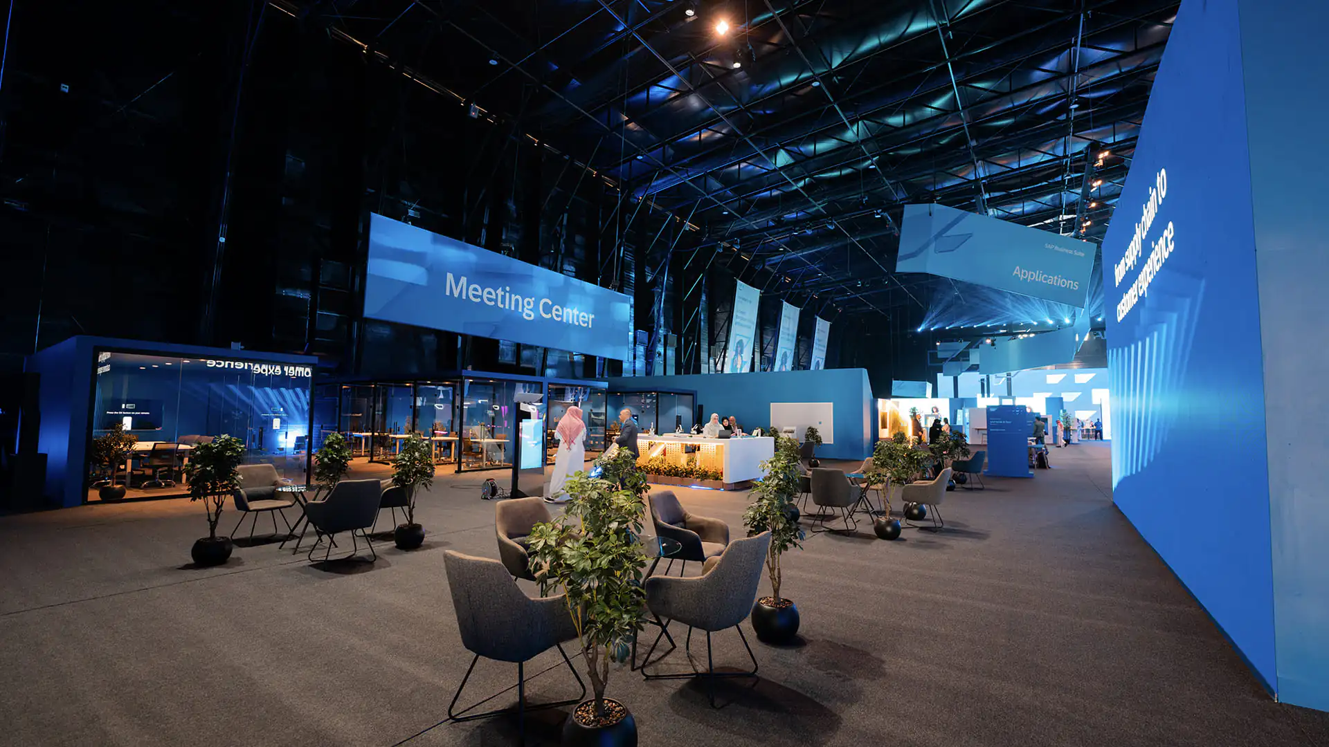 Wide view of SAP NOW AI Tour meeting center with pods, seating, and blue signage.