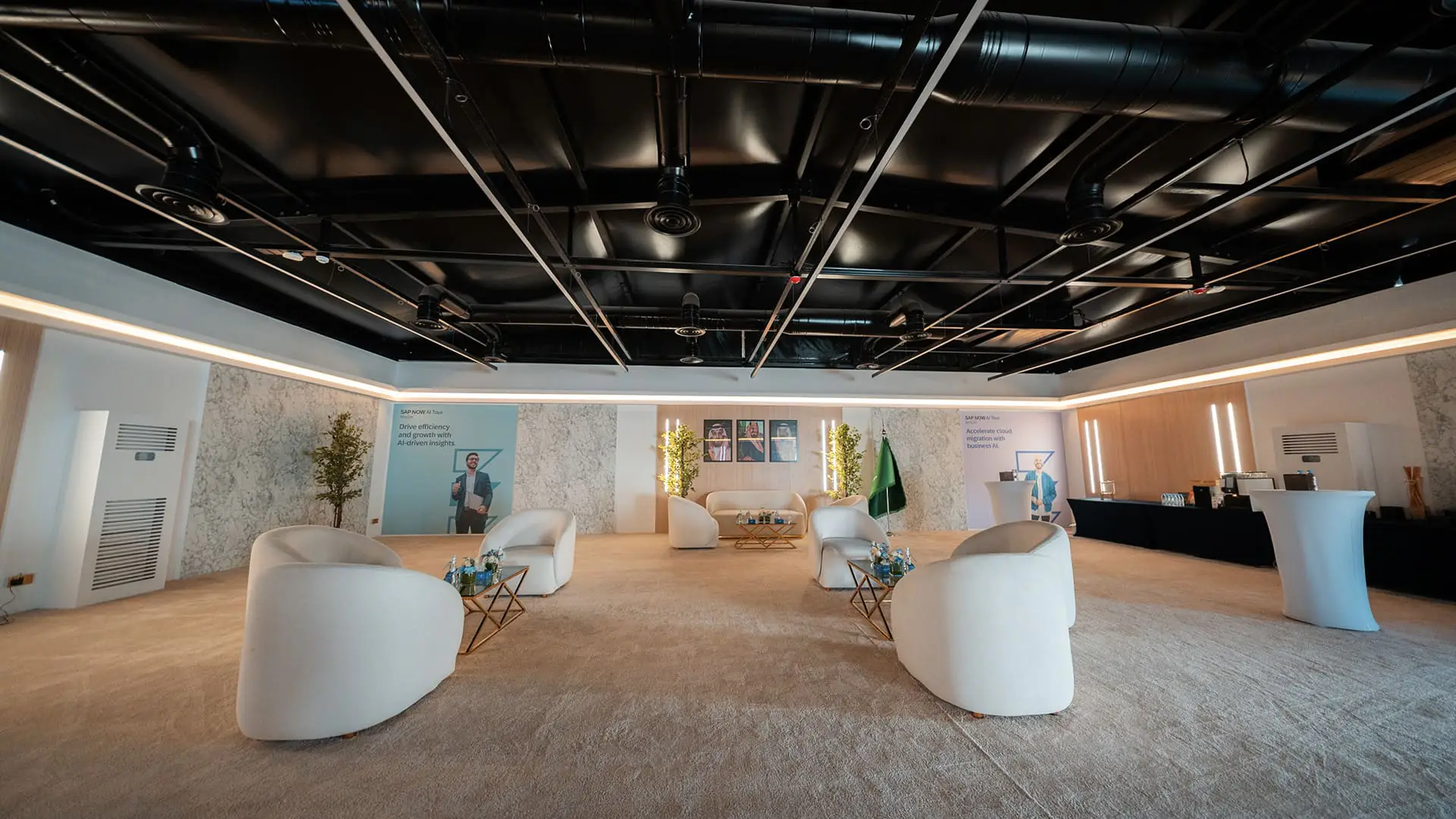 VIP lounge with white seating, Saudi flag, and SAP branding prepared for executives.