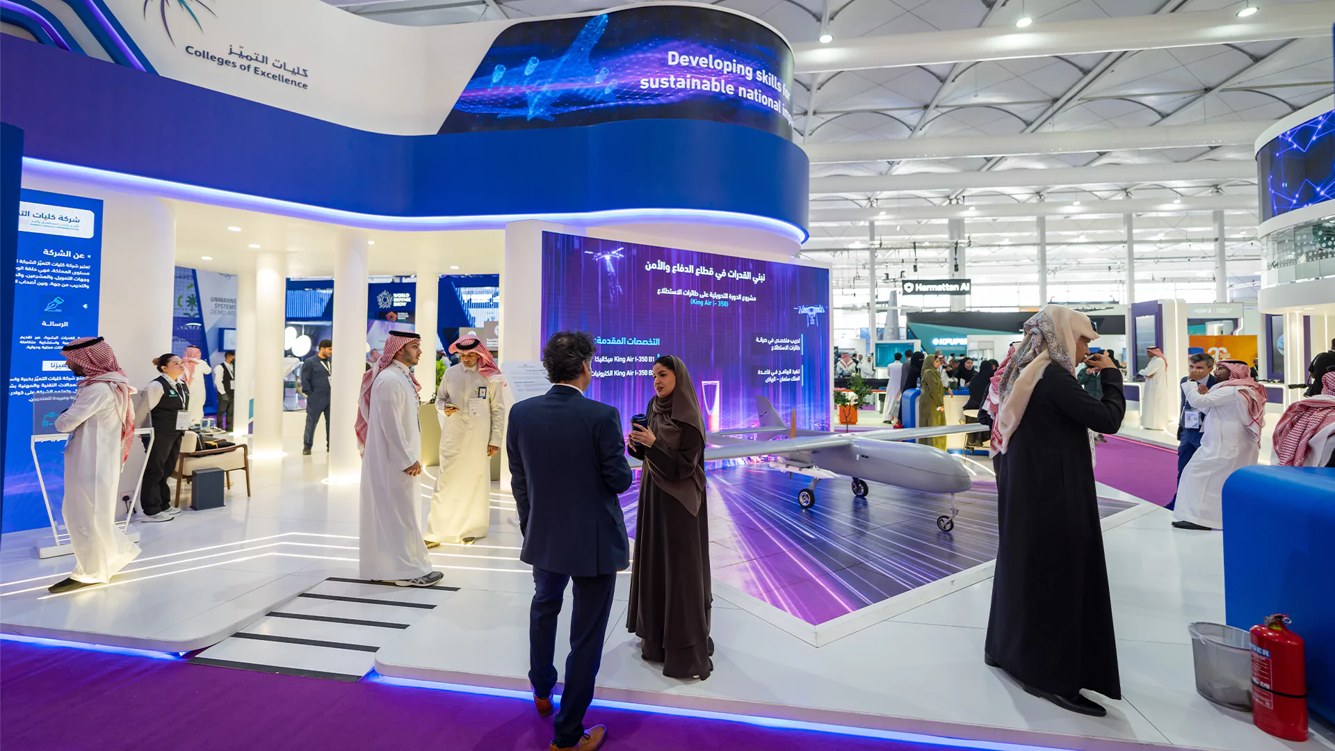 Wide view of the double-deck College of Excellence booth with drone display and visitor engagement, WDS 2026.