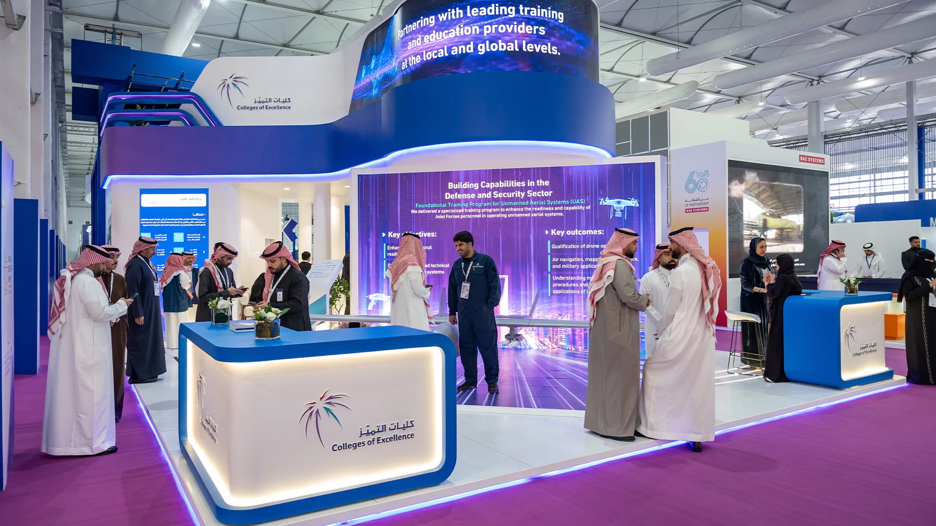 Reception area with branded counters and large LED wall at the College of Excellence booth, World Defense Show 2026.