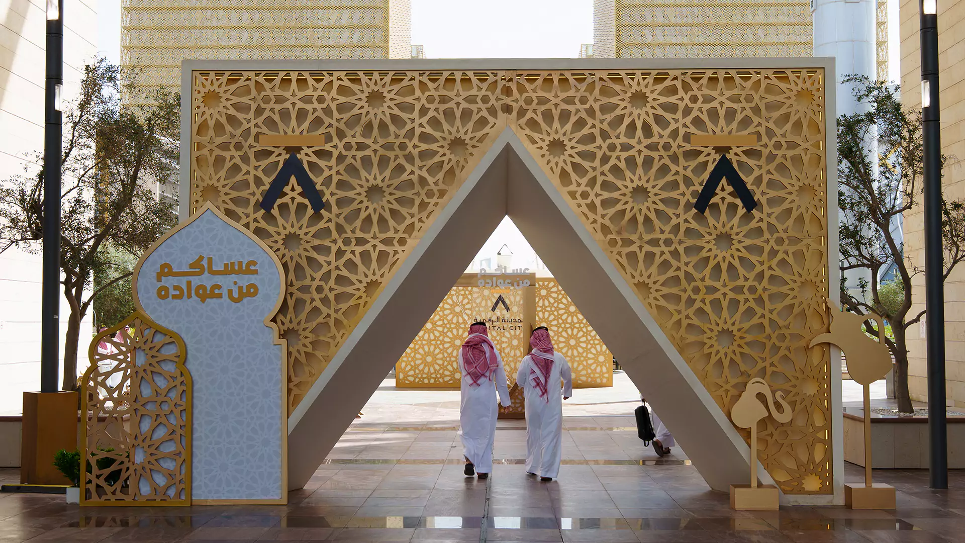 Eid-themed geometric arch at Digital City with Saudi signage and visitors walking through