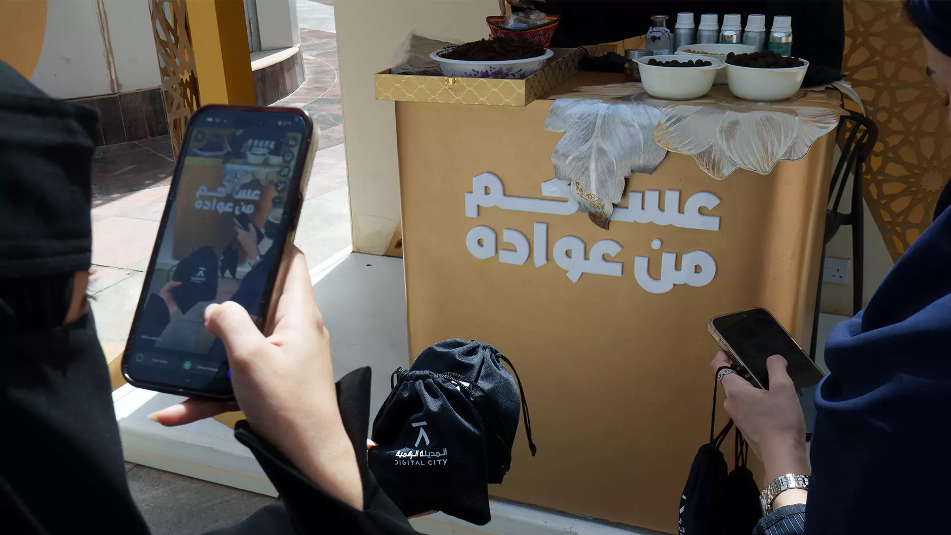 Visitors capturing branded giveaway display with Eid messaging at activation stand