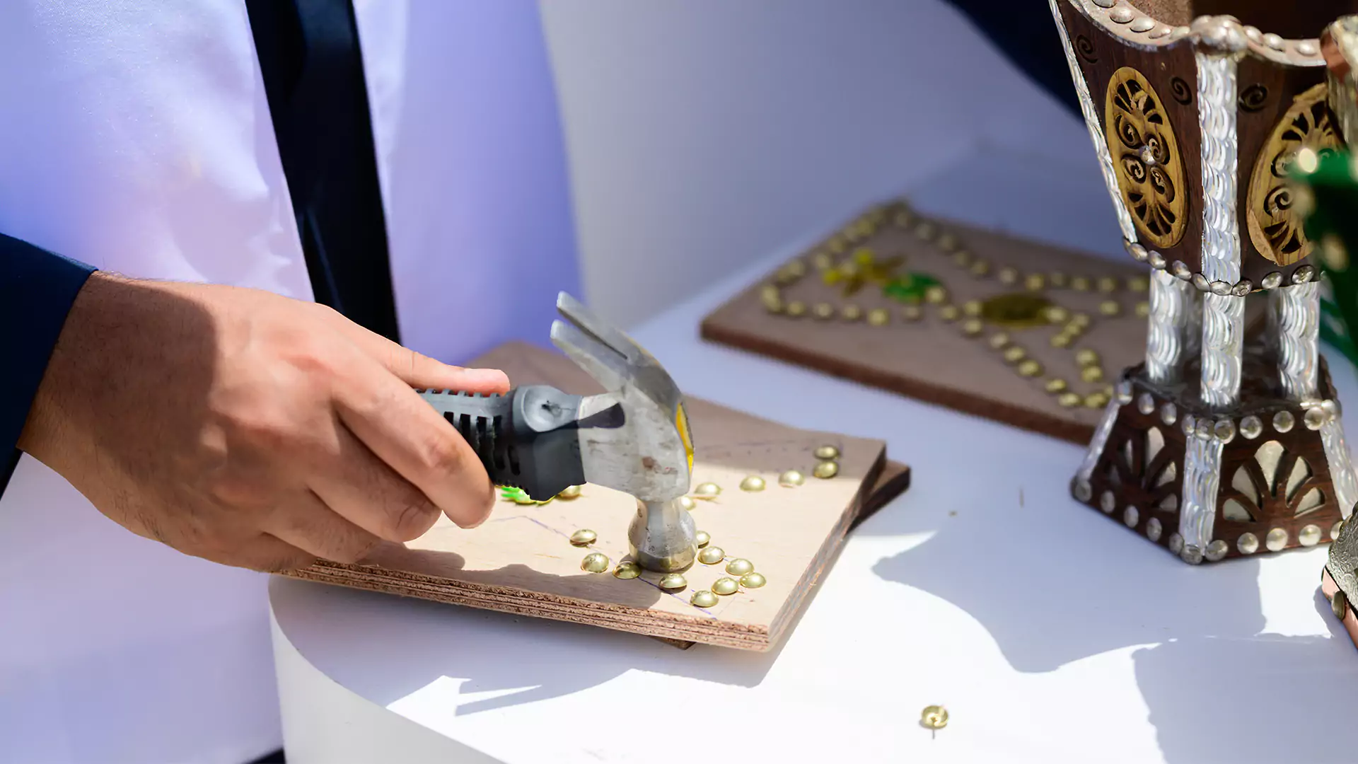 Craftsman hammering decorative studs during live cultural workshop