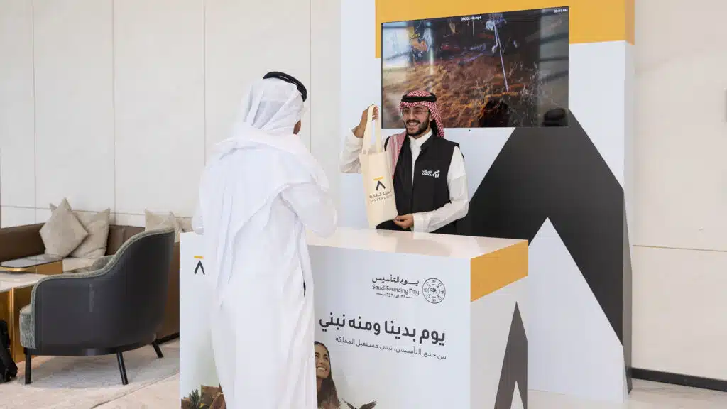Staff handing branded tote bag during Saudi Founding Day activation