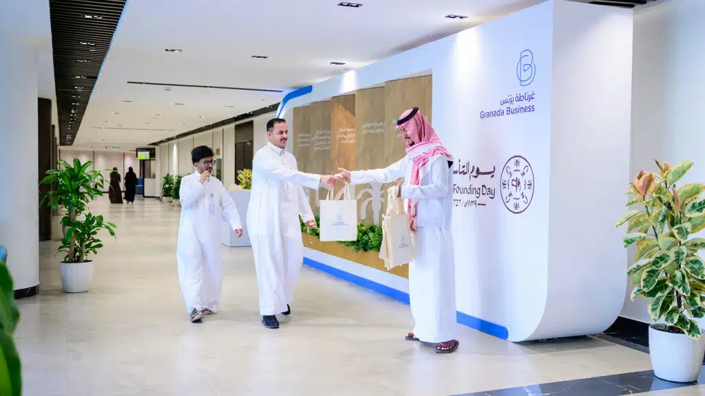 Staff at Granada Business hand out Founding Day giveaway bags in a modern office lobb
